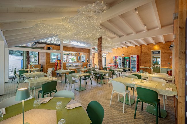 Interno ristorante con tavoli verdi e bianchi, decorazioni soffitto.