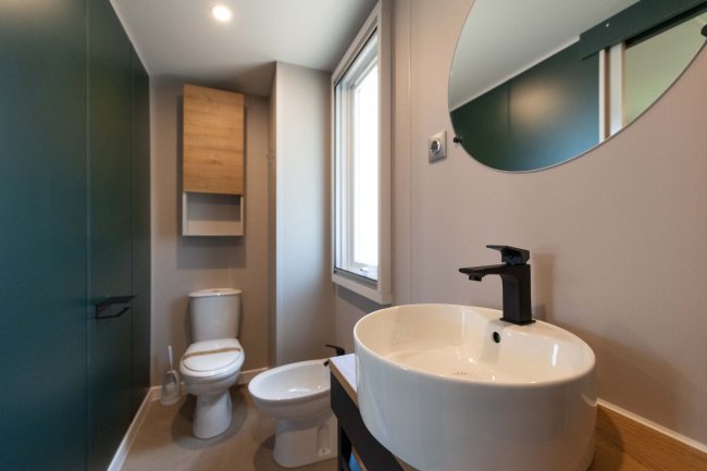 Bagno moderno con lavabo rotondo e specchio.