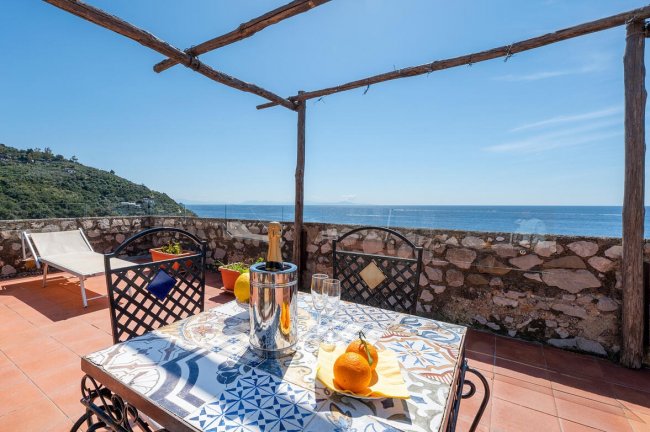 Terrazza con tavolino, vista mare e pergola.