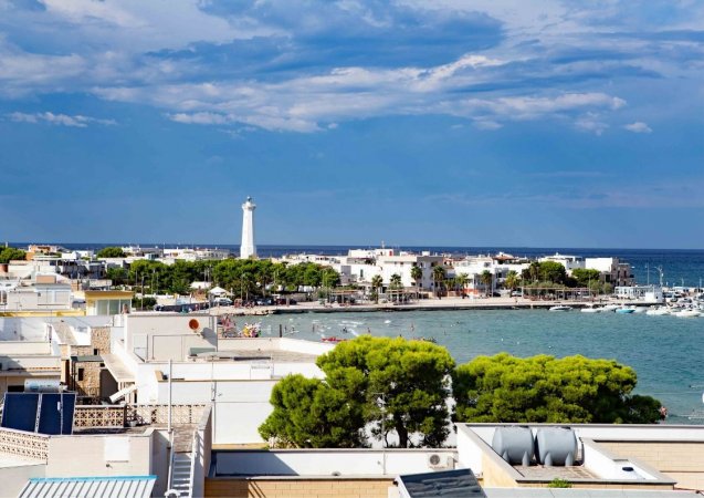 Vista panoramica di una città costiera con un faro e un mare limpido.