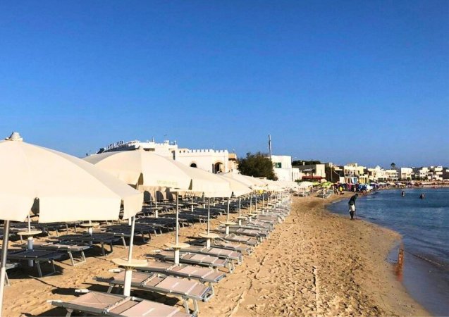 Ombrelloni chiari su una spiaggia sabbiosa vicino al mare.