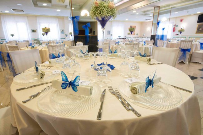 Sala per eventi con tavoli rotondi decorati.
