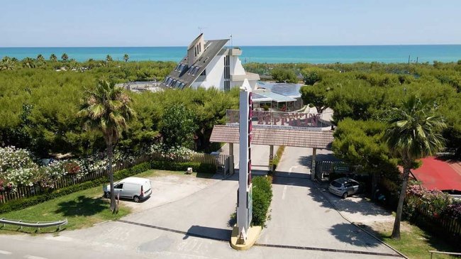 Strada d'ingresso con vegetazione e vista mare.