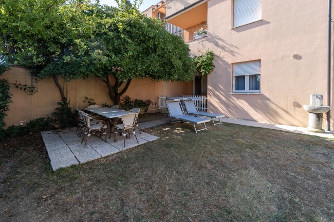 Giardino con tavolo e sdraio sotto un albero.