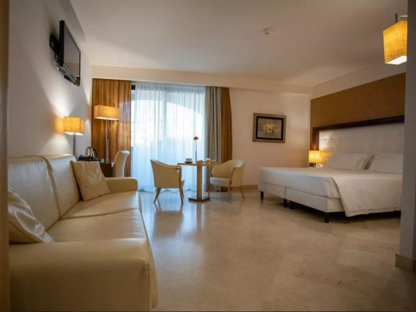 Camera d'hotel con letto, divano e tavolo.