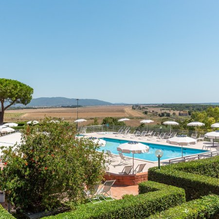 Piscina con ombrelloni e campagna intorno.
