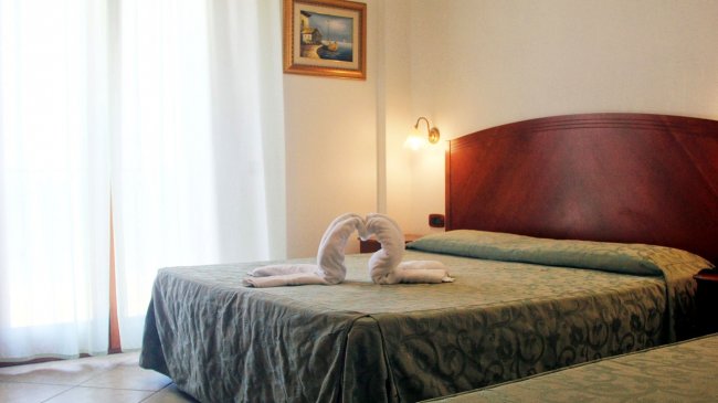 Camera con letto matrimoniale e asciugamani a forma di cigni.