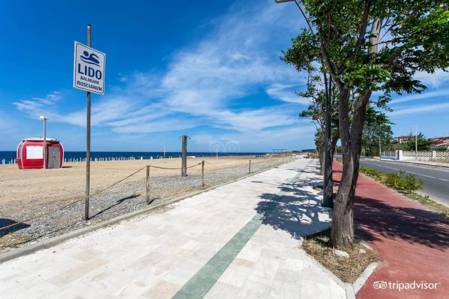 Lungomare con spiaggia e cielo blu.