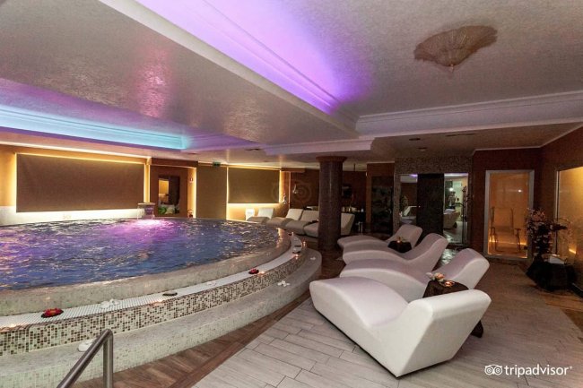 Piscina interna con lettini bianchi.