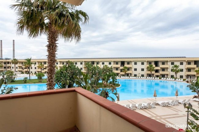 Balcone con vista su piscina e palme.