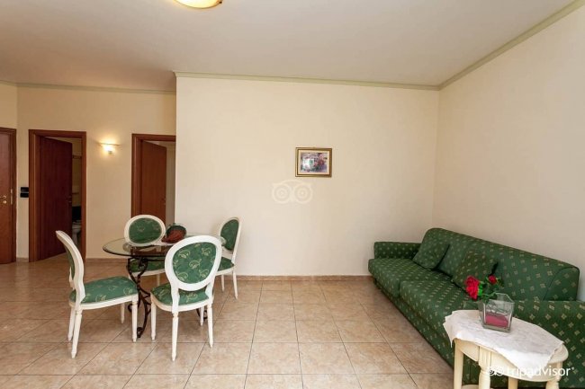 Sala con divano verde, tavolo rotondo e sedie abbinate.