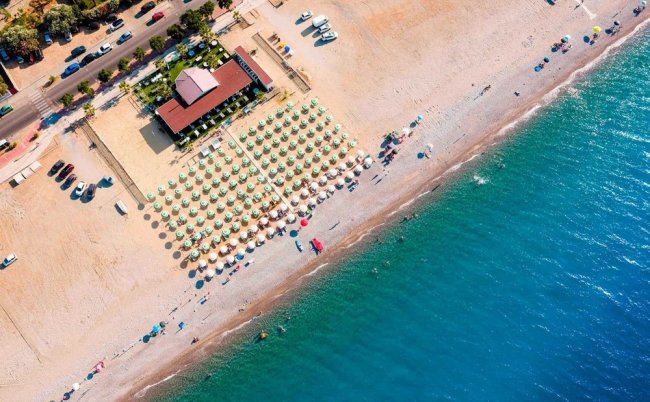 Vista aerea di una spiaggia con ombrelloni e mare.