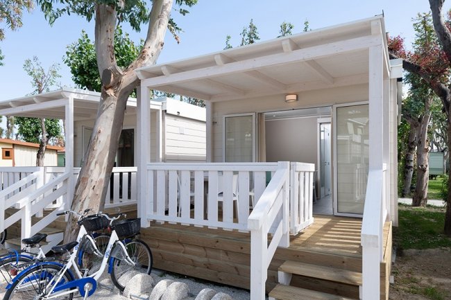 Veranda in legno bianco con biciclette parcheggiate.