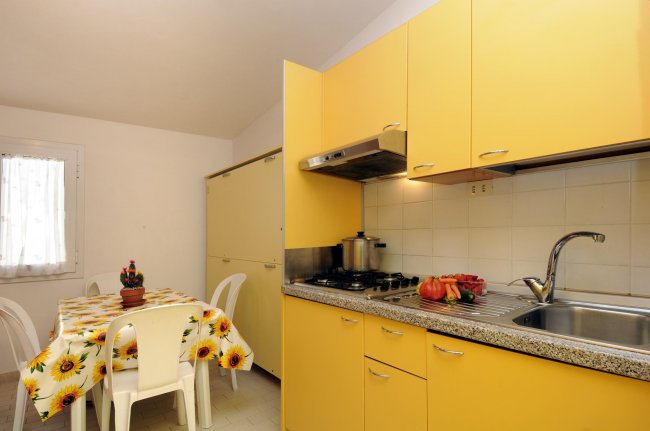 Cucina con mobili gialli e tavolo con tovaglia a girasoli.