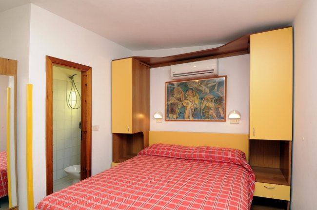 Stanza con letto matrimoniale, mobili gialli e quadro.