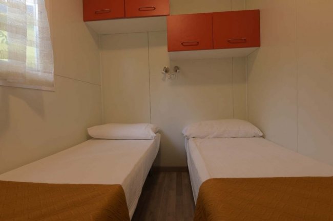 Camera con due letti singoli e armadietto rosso.