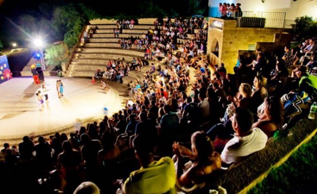 Spettatori seduti in un anfiteatro all'aperto.