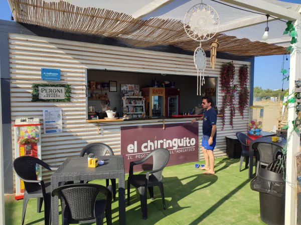 Bar sulla spiaggia con tavoli e sedia in plastica.