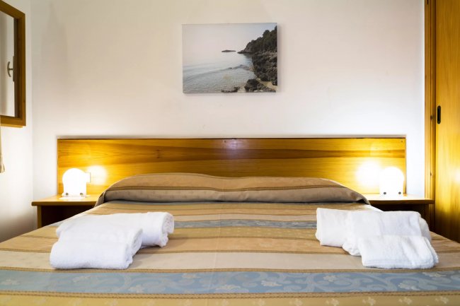 Letto con coperte a righe e asciugamani piegati.