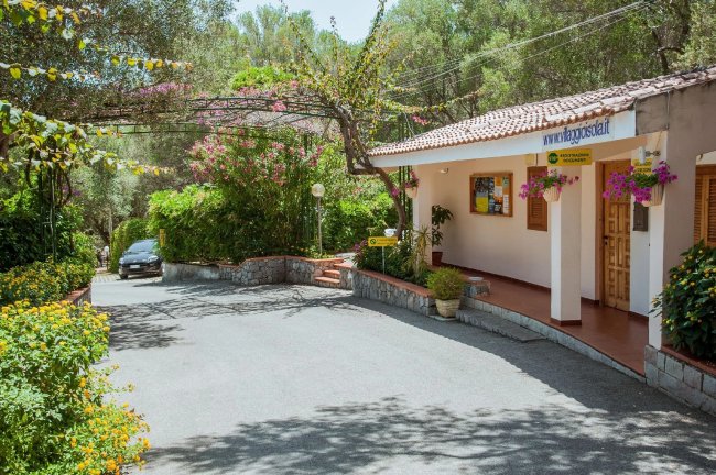 Ingresso albergo circondato da piante fiorite.