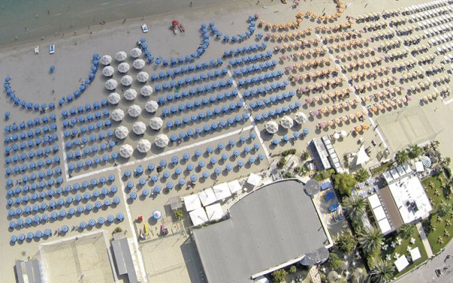 Vista dall'alto di spiaggia con ombrelloni colorati.