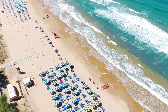Spiaggia con ombrelloni blu e onde.
