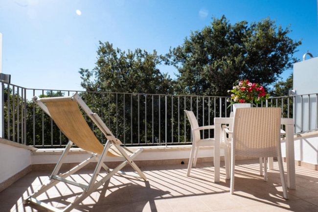 Terrazzino con sedia a sdraio e tavolo bianco.