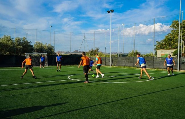 Persone giocano una partita di calcetto su un campo in erba sintetica all'aperto.