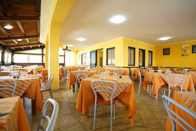 Una sala da pranzo con tavoli apparecchiati con tovaglie arancioni.