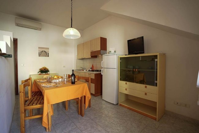 Interno di cucina con tavolo apparecchiato, frigo e credenza.