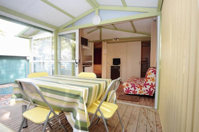 Veranda con tavolo a righe e sedie gialle.