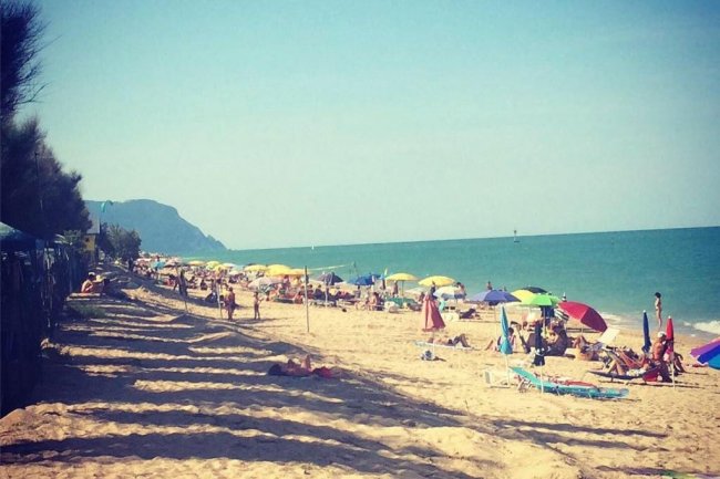 Spiaggia affollata con ombrelloni colorati.