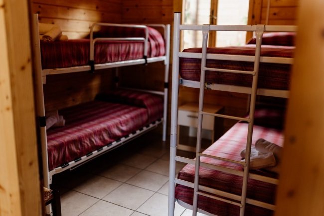 Stanza con letti a castello e coperte rosse.